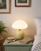 Dolce mushroom nightstand lamp with a cream glossy base and white glass dome on a green nightstand