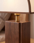 Close-up of the Halvo lamp's solid walnut block base and brass-finish fitting