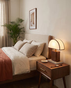Halvo half-dome walnut nightstand lamp in a warm bedroom, seen from the right