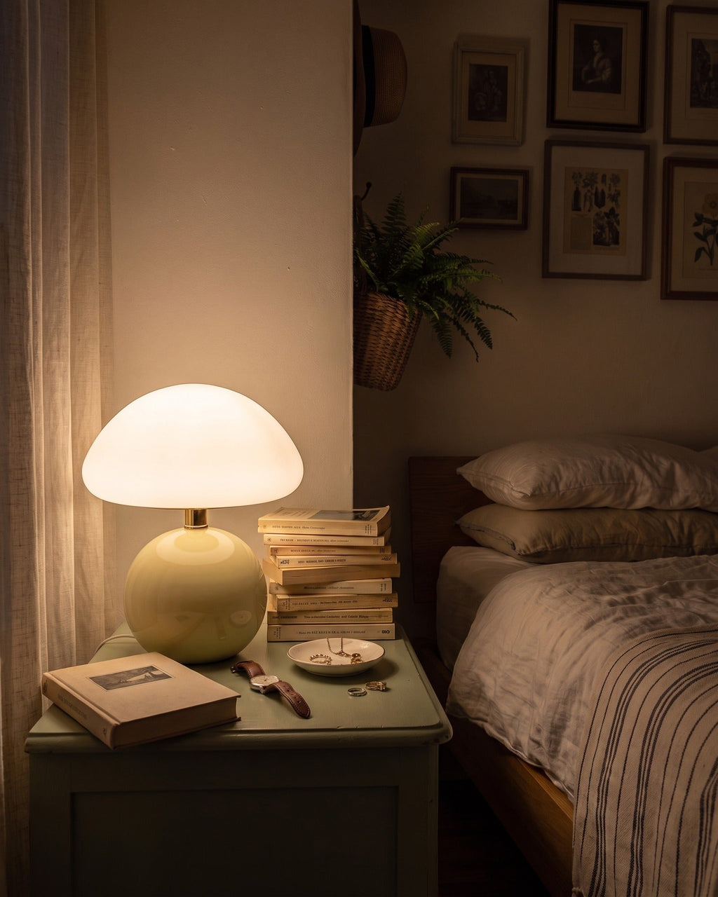 Cream Dolce mushroom lamp glowing on a nightstand in the evening