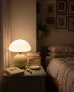 Cream Dolce mushroom lamp glowing on a nightstand in the evening
