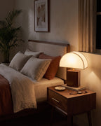 Halvo half-dome walnut lamp glowing on a nightstand in the evening
