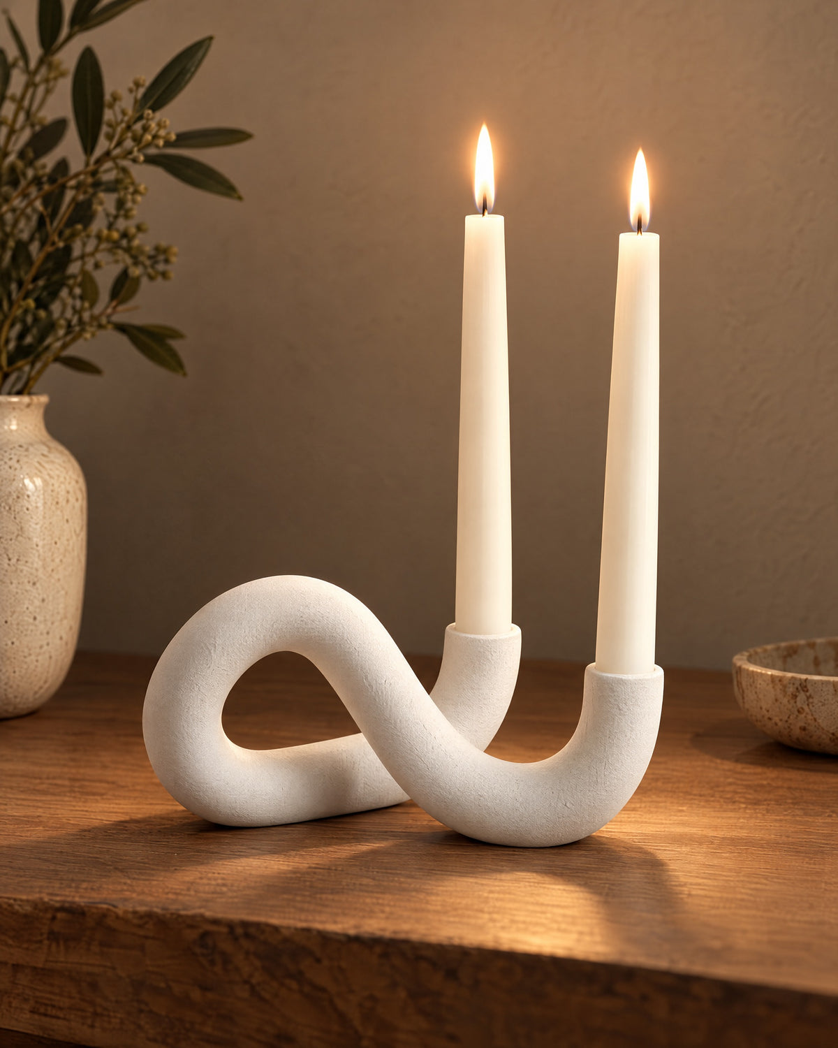 White: Knot Sculptural Double Candle Holder, lit, on a styled surface in the evening