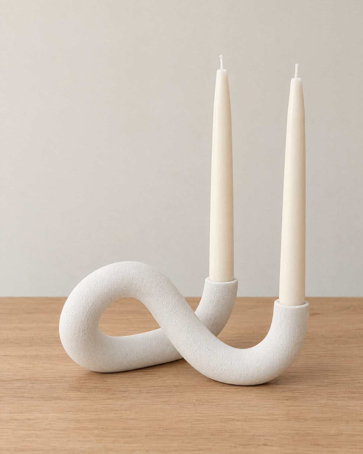 White: Knot Sculptural Double Candle Holder on a light oak tabletop against a seamless studio backdrop