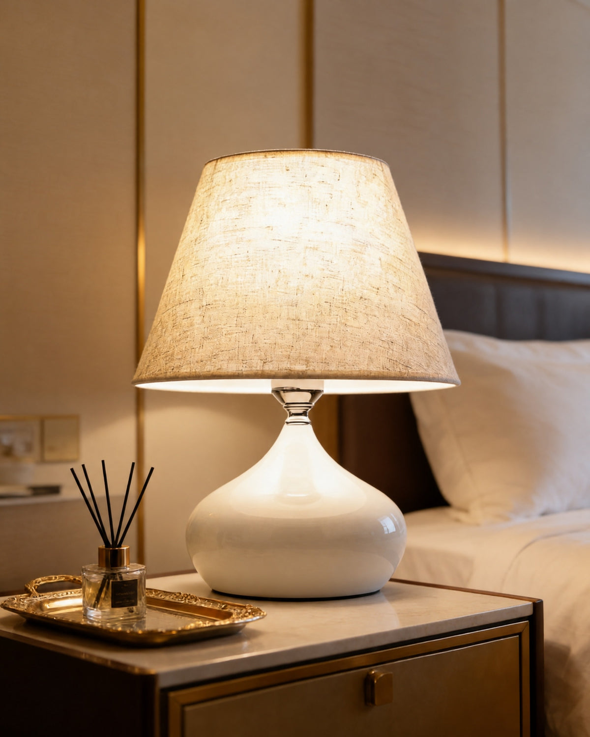 Aria glossy white ceramic lamp with a linen empire shade on a nightstand