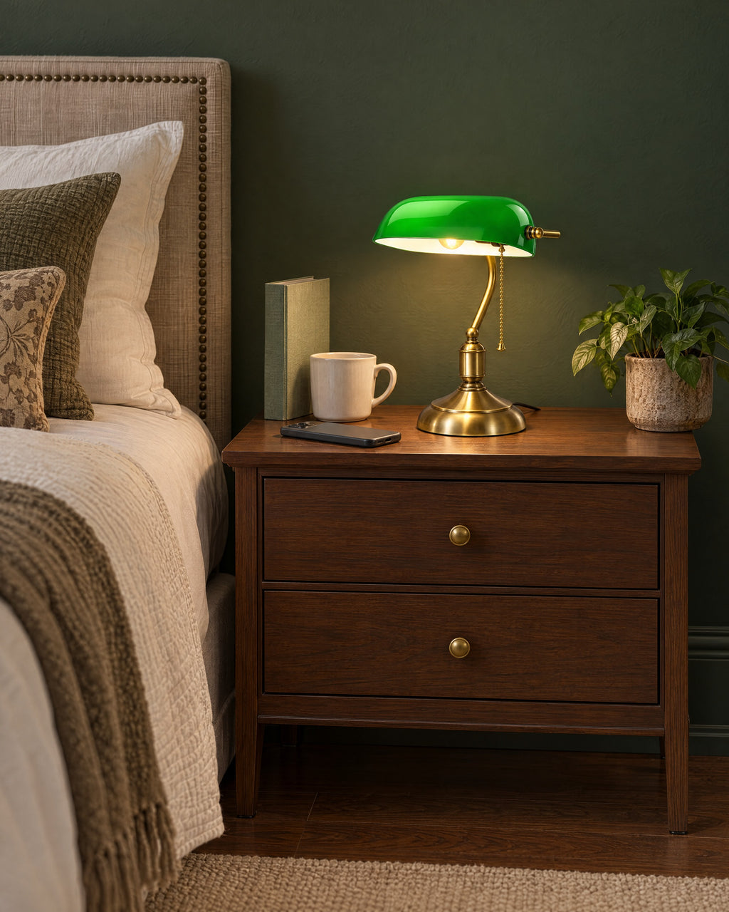 Bankers Green Glass Nightstand Lamp on a standard nightstand with a paperback, phone and mug for scale