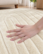 A hand resting on the carved high-low pile of the Beige High-Low Area Rug, Carved Arcs, Washable