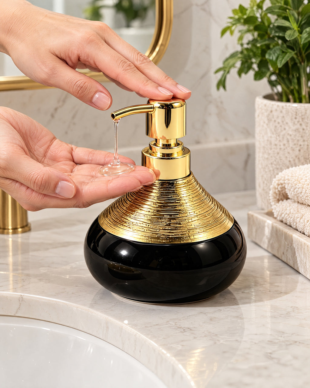 A hand pressing the pump of the Soap Dispenser, Ceramic, Black with Brushed Gold, 9 oz