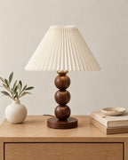Walnut: Bobbin Trio Wood Nightstand Lamp in walnut on a nightstand top against a light studio backdrop