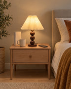 Walnut: Bobbin Trio Wood Nightstand Lamp in walnut on a standard nightstand with a book, phone and mug for scale