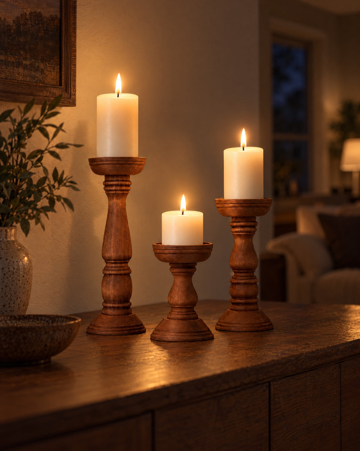 Bosco Farmhouse Wood Candle Holders, Set of 3 with candles lit in the evening on a sideboard in a dim living room