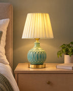 Celadon Carved Gourd Nightstand Lamp switched on on a nightstand in the evening
