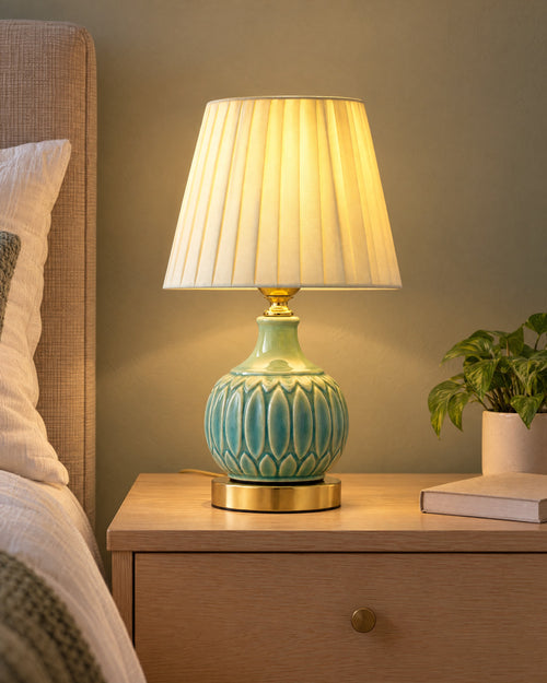 Celadon Carved Gourd Nightstand Lamp switched on on a nightstand in the evening