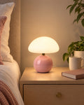 Pink: Dolce Mushroom Nightstand Lamp in pink lit on a nightstand in the evening