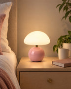 Pink: Dolce Mushroom Nightstand Lamp in pink lit on a nightstand in the evening