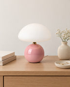 Pink: Dolce Mushroom Nightstand Lamp in pink on a nightstand top against a light studio backdrop
