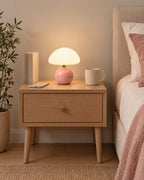 Pink: Dolce Mushroom Nightstand Lamp in pink on a standard nightstand with a book, phone and mug for scale