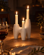 Duna Sculptural Ceramic Candle Holder with candles lit at night on a dinner table