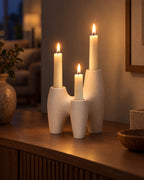 Duna Sculptural Ceramic Candle Holder with candles lit in the evening on a sideboard in a dim living room