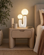 Duo Globe Sculptural Nightstand Lamp on a standard nightstand with a paperback, phone and mug for scale