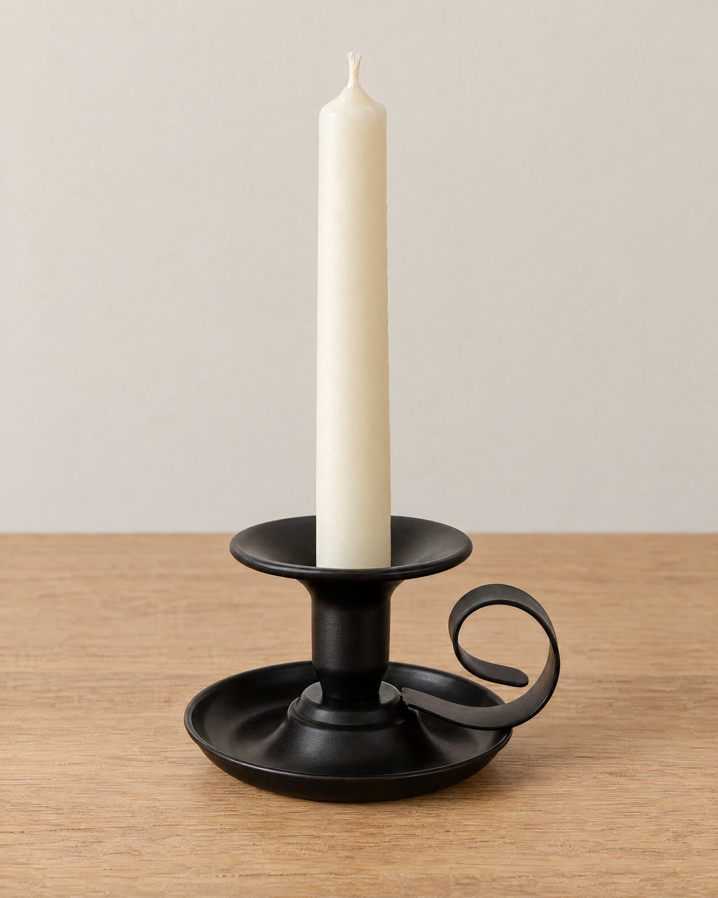 Tazza Iron Teacup Candle Holder on a light oak tabletop against a seamless studio backdrop