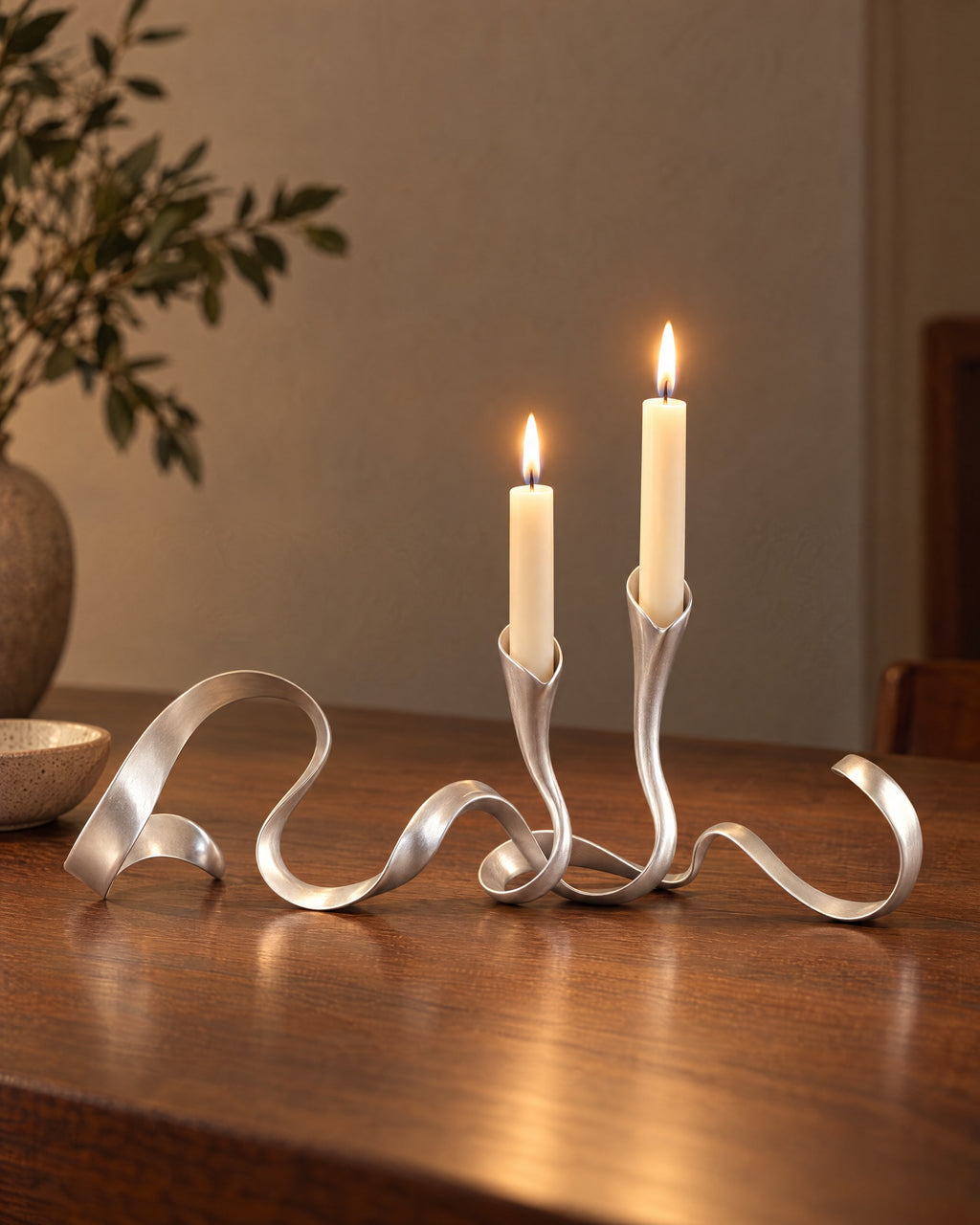 Silver: Ribbon Metal Candelabra, lit, on a styled surface in the evening