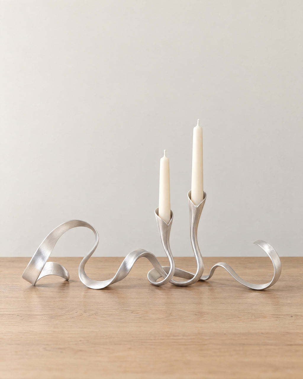 Silver: Ribbon Metal Candelabra on a light oak tabletop against a seamless studio backdrop