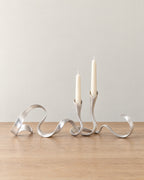 Silver: Ribbon Metal Candelabra on a light oak tabletop against a seamless studio backdrop