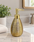 Teardrop Soap Dispenser, Ceramic, Brushed Gold on a bathroom vanity in soft daylight