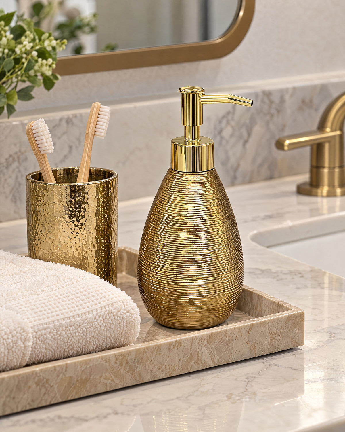 Teardrop Soap Dispenser, Ceramic, Brushed Gold styled on a tray with bathroom accessories