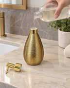 The Teardrop Soap Dispenser, Ceramic, Brushed Gold being refilled, pump set aside