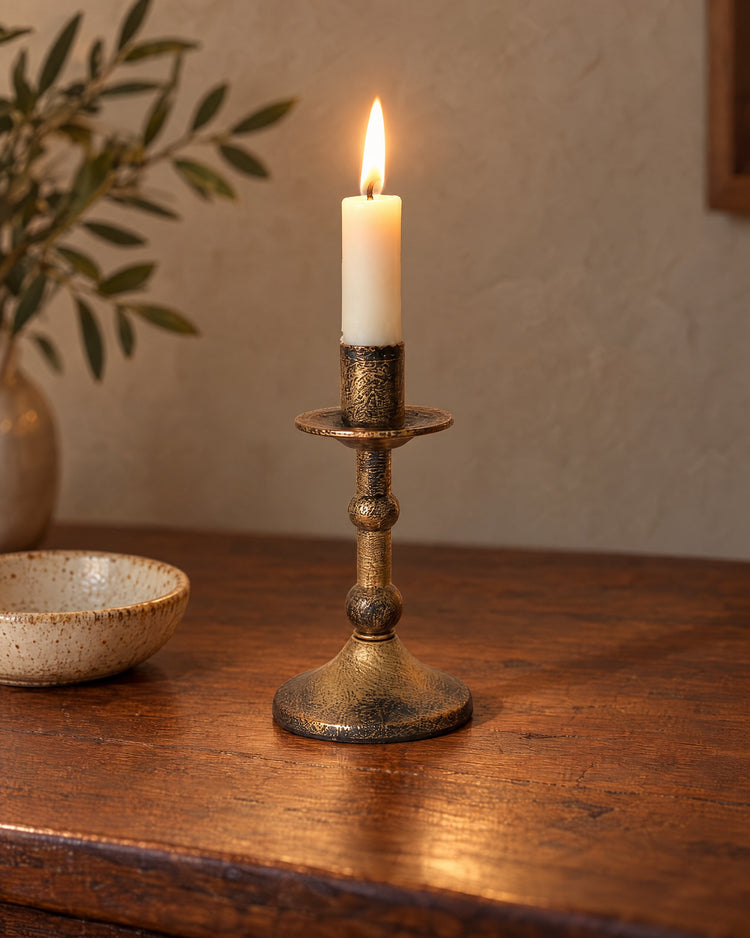 Heritage Distressed Metal Candlestick, lit, on a styled surface in the evening