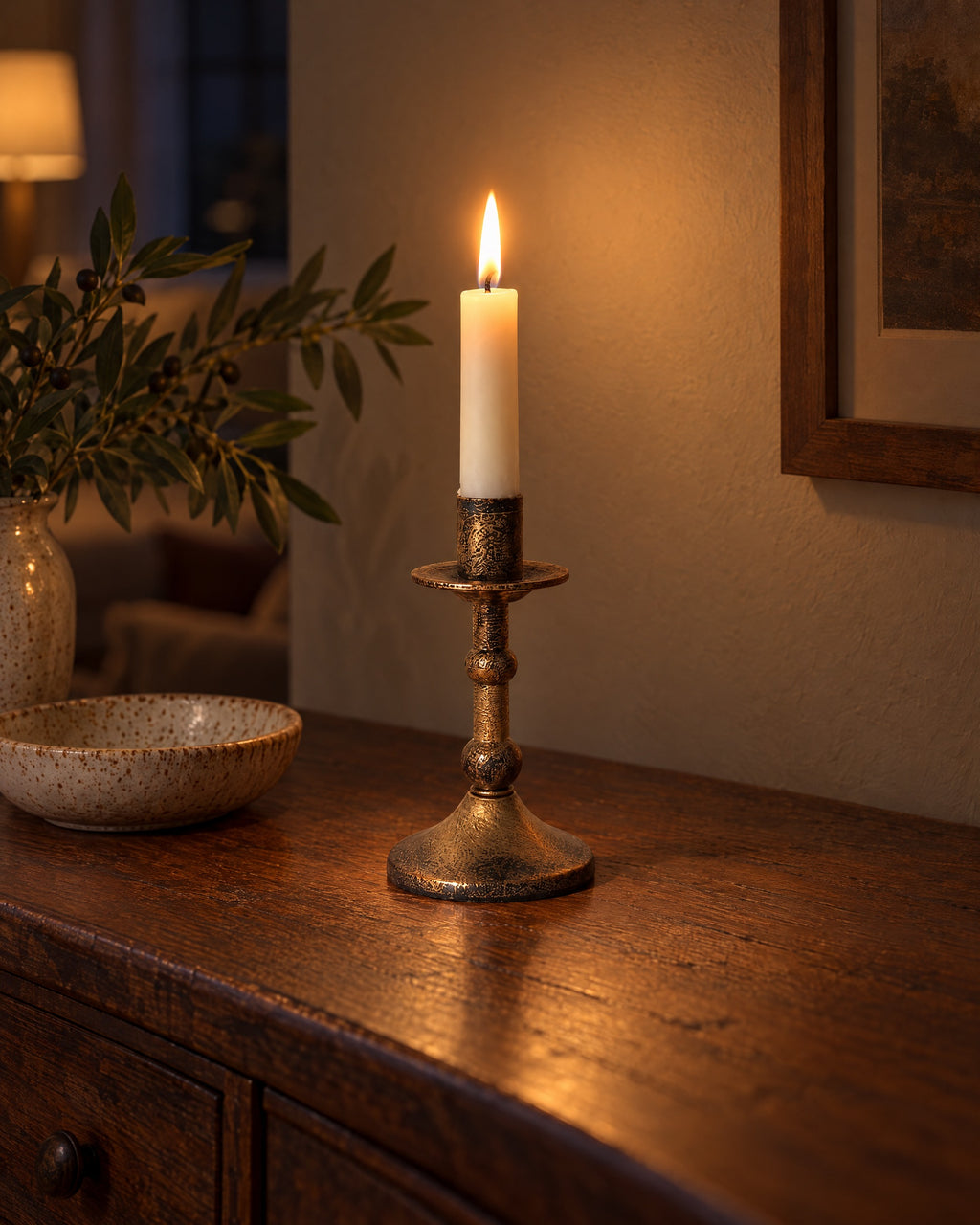 Heritage Distressed Metal Candlestick with candles lit in the evening on a sideboard in a dim living room