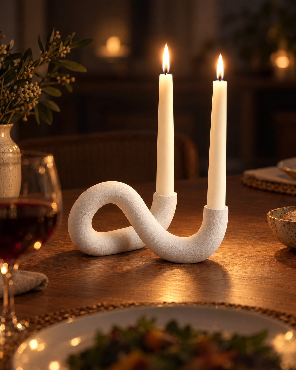 White: Knot Sculptural Double Candle Holder with candles lit at night on a dinner table