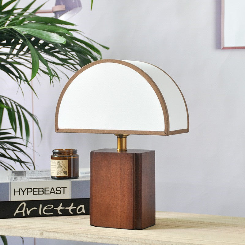 Halvo half-dome walnut lamp next to a stack of books on a side table
