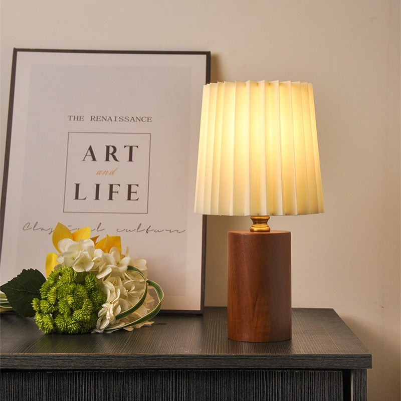 Linnea walnut lamp with a pleated shade next to an art print and flowers