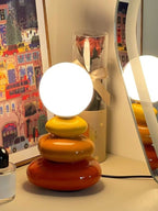 Pebble Stack lamp with orange and yellow glazed ceramic pebbles and a white glass globe