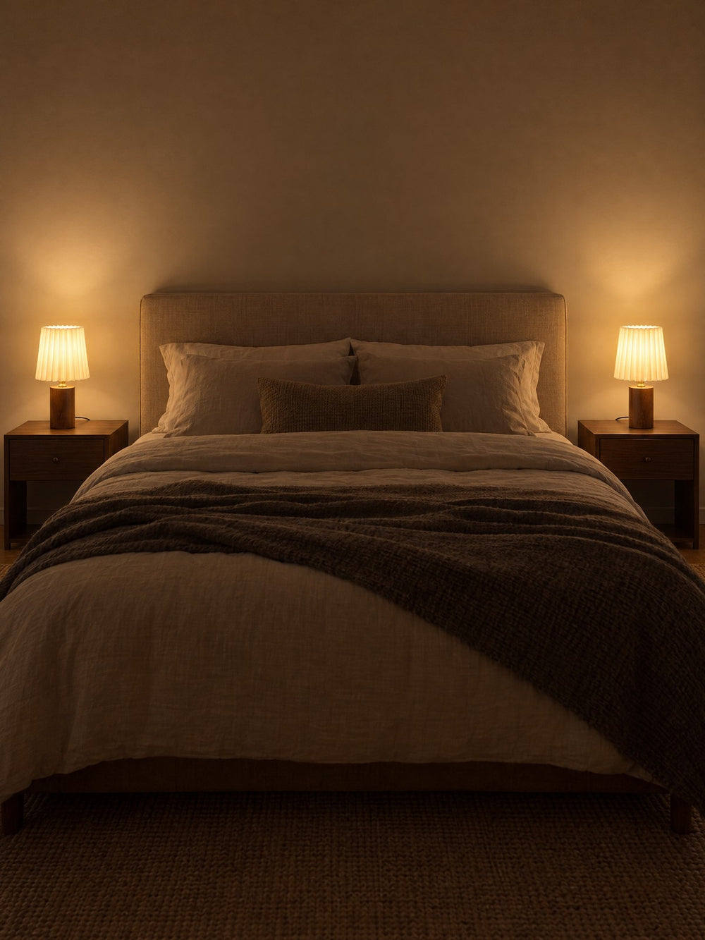 Two Linnea Pleated Wood Nightstand Lamp lamps on either side of a bed at night