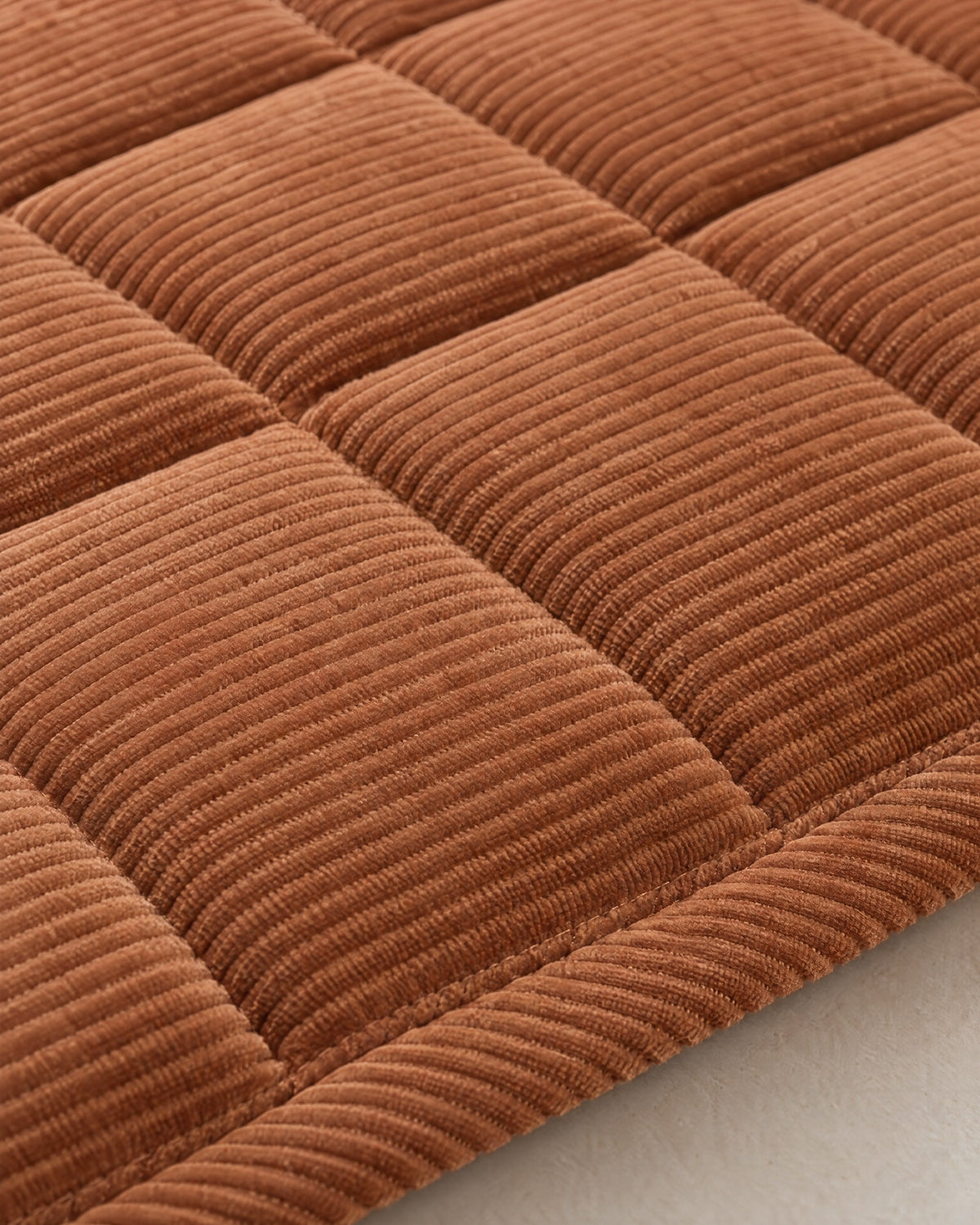 Chestnut Haze: Close-up of the fabric and edge of the Metro Line Quilted Couch Cover Mat
