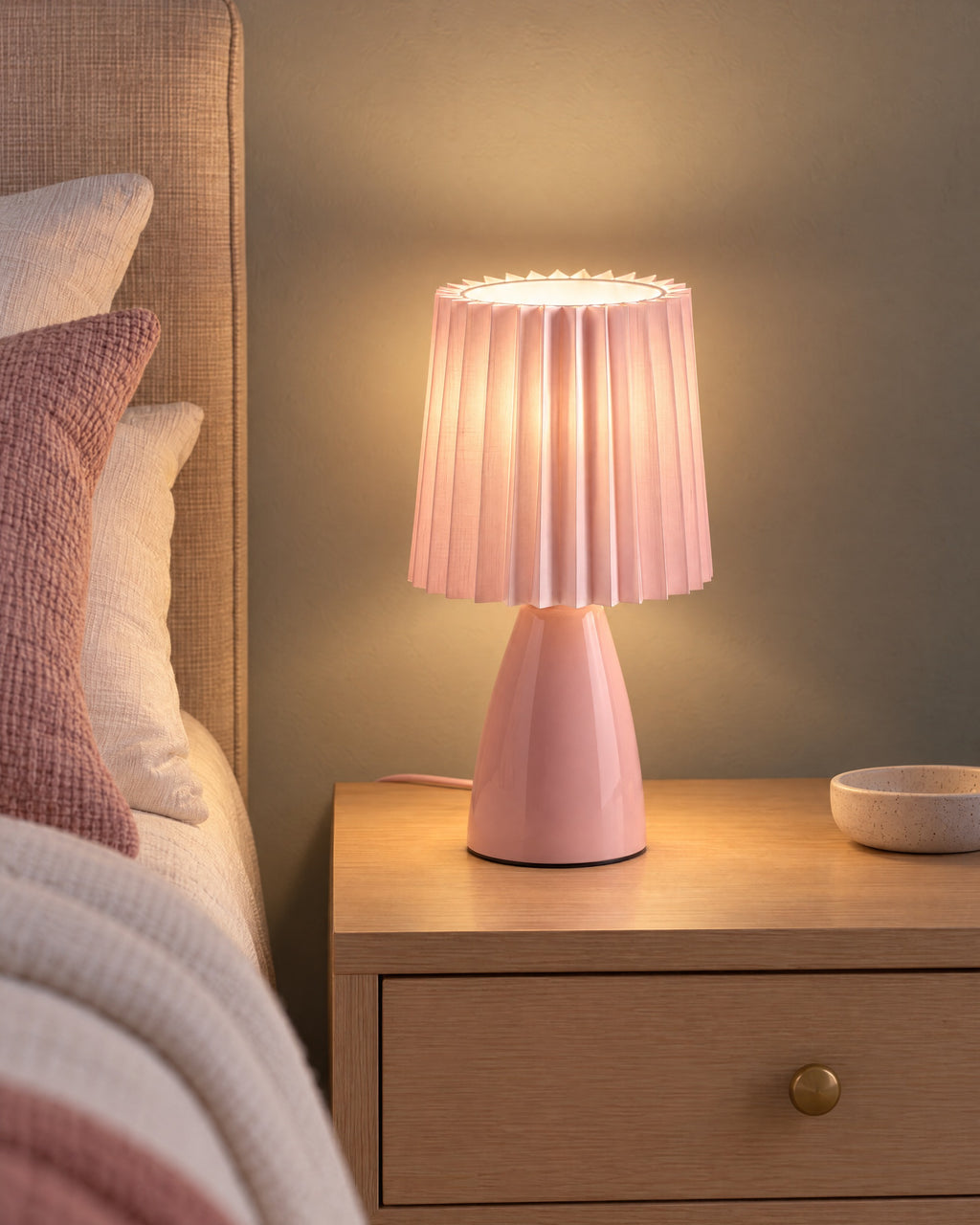 Pink: Milkshake Ceramic Cone Nightstand Lamp switched on on a nightstand in the evening