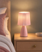 Pink: Milkshake Ceramic Cone Nightstand Lamp switched on on a nightstand in the evening