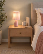 Pink: Milkshake Ceramic Cone Nightstand Lamp on a standard nightstand with a paperback, phone and mug for scale