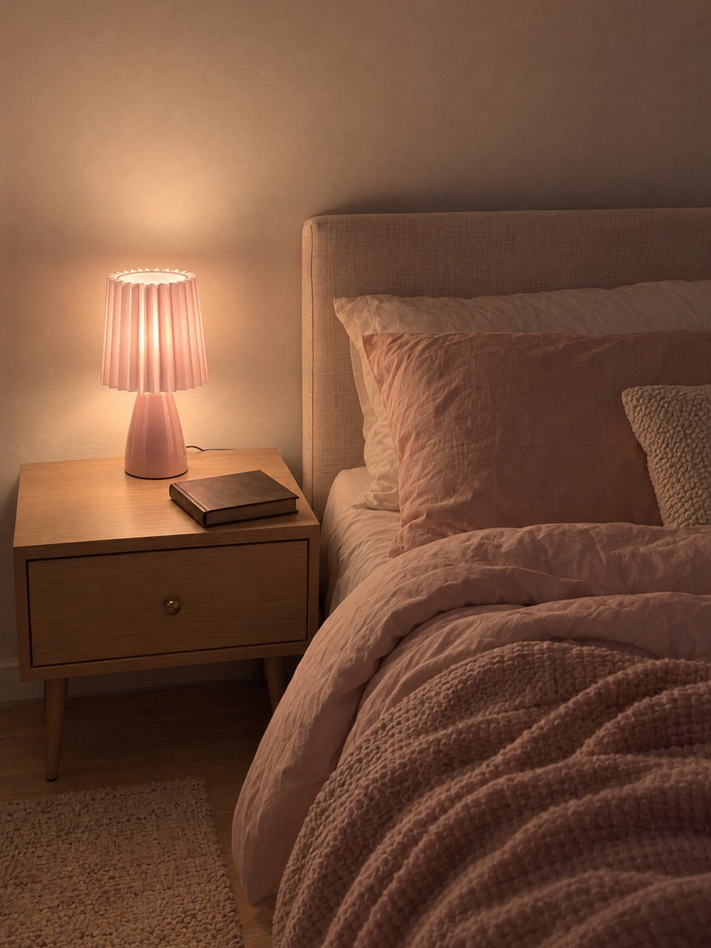 Milkshake Ceramic Cone Nightstand Lamp lit on a nightstand at night
