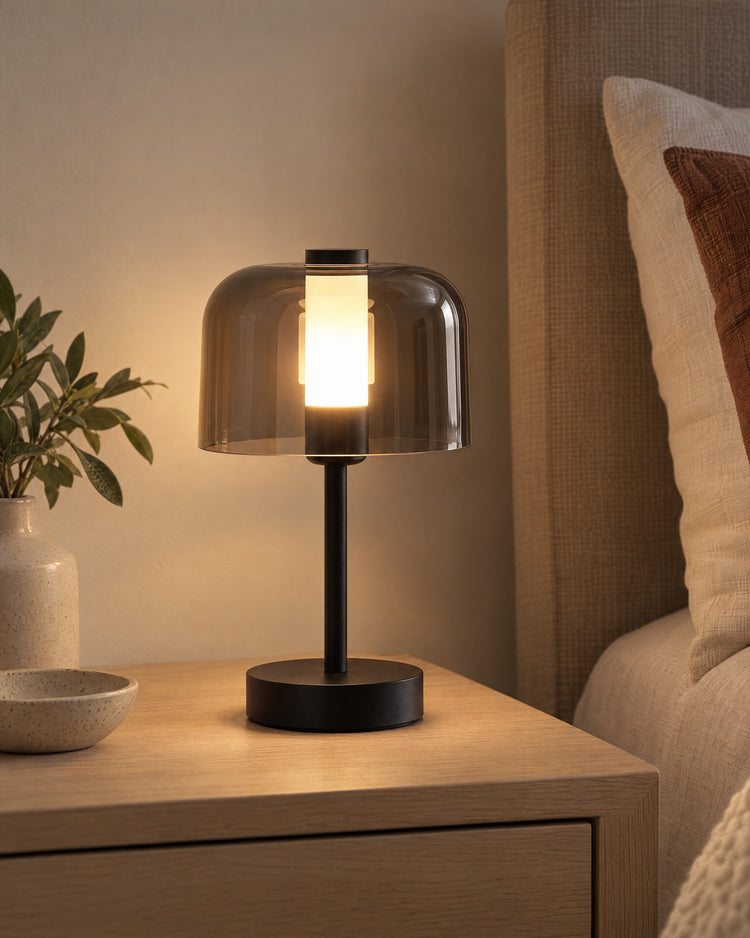 Black: Noir Cordless Dome Nightstand Lamp in black lit on a nightstand in the evening