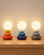 All colourways of the Pebble Stack Ceramic Nightstand Lamp side by side: Orange, Blue, Grey