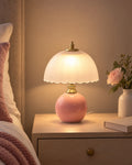 Pink: Petal Dome Ceramic Nightstand Lamp in pink lit on a nightstand in the evening