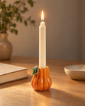 Zucca Pumpkin Ceramic Candle Holder, lit, on a styled surface in the evening