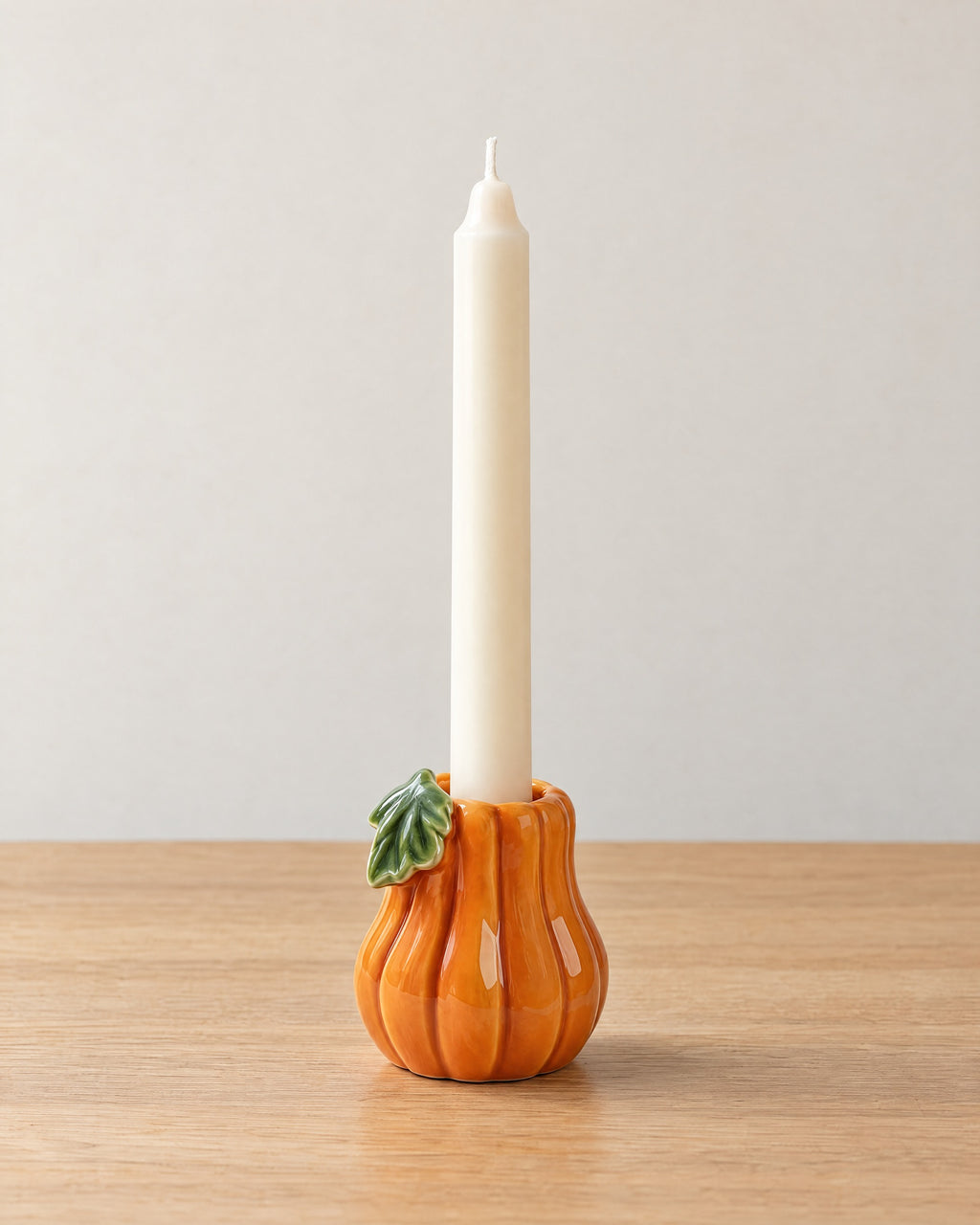 Zucca Pumpkin Ceramic Candle Holder on a light oak tabletop against a seamless studio backdrop