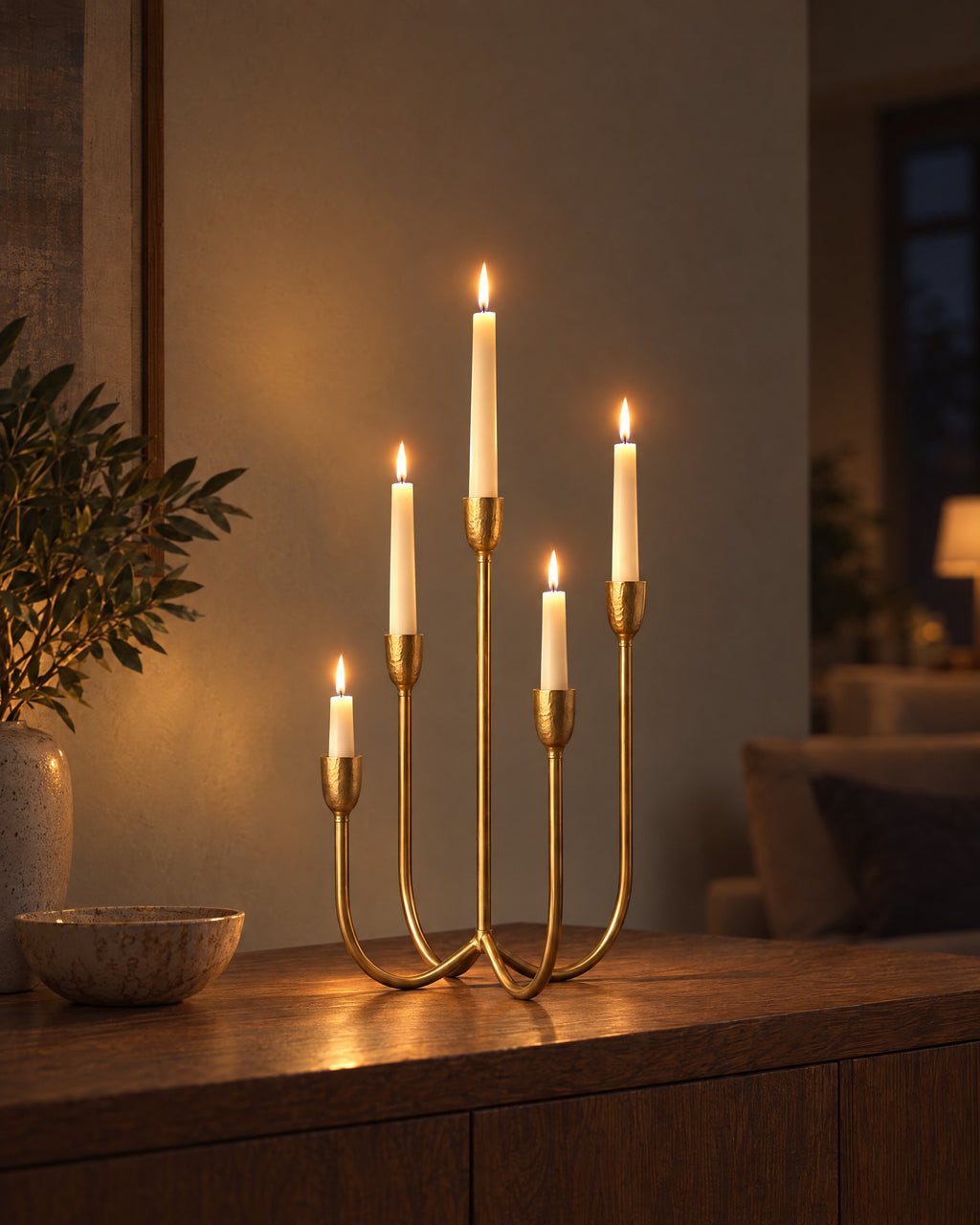 Quinta Five-Arm Iron Candelabra with candles lit in the evening on a sideboard in a dim living room