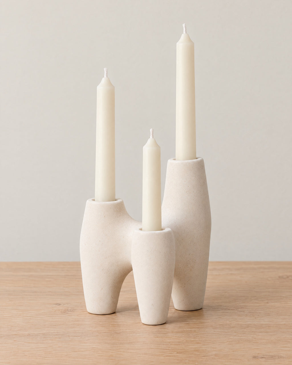 Duna Sculptural Ceramic Candle Holder on a light oak tabletop against a seamless studio backdrop